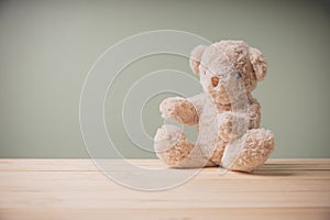 Single brown teddy bear sitting on old wooden table filling sad, alone with copy space. This cuddly fluffy doll is perfect for