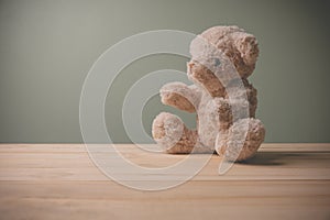 Single brown teddy bear sitting on old wooden table filling sad, alone with copy space. This cuddly fluffy doll is perfect for