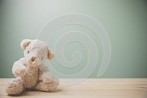 A single brown teddy bear sitting on an old wooden table filling sad, alone with copy space. This cuddly fluffy doll is perfect