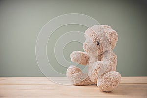 Single brown teddy bear sitting on old wooden table filling sad, alone with copy space. This cuddly fluffy doll is perfect for
