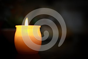 Single burning candle with dark background.