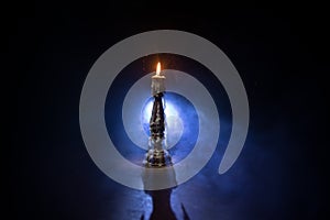 Single burning candle. Light of flame and flowing candle wax, dark background