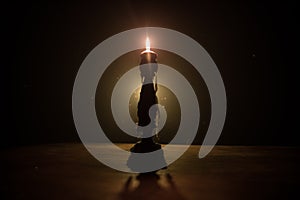 Single burning candle. Light of flame and flowing candle wax, dark background
