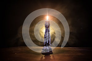 Single burning candle. Light of flame and flowing candle wax, dark background