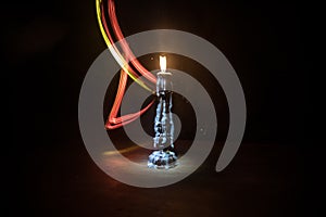 Single burning candle. Light of flame and flowing candle wax, dark background