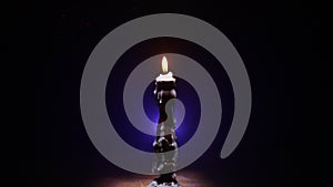 Single burning candle. Light of flame and flowing candle wax, dark background. Slider shot