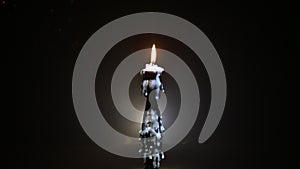 Single burning candle. Light of flame and flowing candle wax, dark background. Slider shot