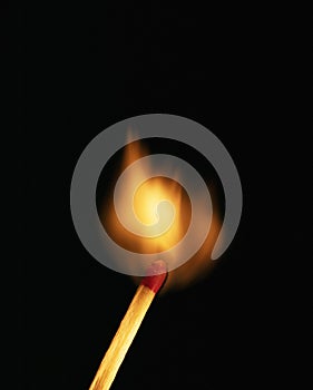 Single burning match on black background