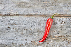 Single chili pepper on wood.