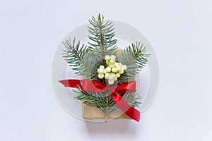 Single Christmas present with fir branch, red bow and branch of plant with white berries