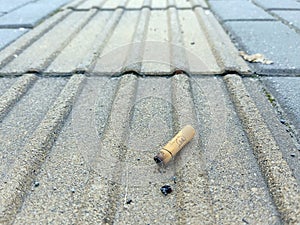 single cigarette butt on the sideway road. foreground close up and blue background. stock photo