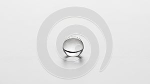 A single clear water droplet rests on a smooth white surface