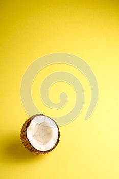 Single coconut fruit on yellow plain background, abstract food tropical concept, copy space