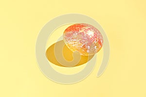 Single colorful easter egg on vibrant yellow background with decorative