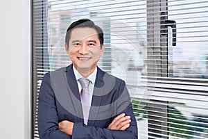 Single confident and handsome male businessman in blue suit and necktie with grin leaning on window outdoors