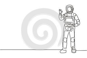 Single continuous line drawing astronaut stands with gesture okay wearing space suit exploring earth, moon, other planets in the