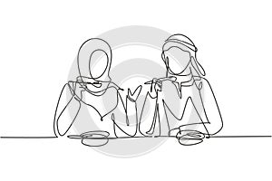 Single continuous line drawing young Arab couple having salad meal around table. Happy male female sitting eating lunch together