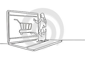 Single continuous line drawing young Arabian woman shopping through laptop screen with shopping cart. E-commerce, digital