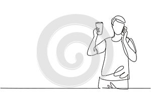 Single continuous line drawing young handsome man drinking orange juice while making phone call with smartphone and having