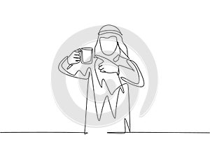 Single continuous line drawing of young muslim office worker pointing finger to mug of coffee. Arab middle east male cloth shmagh photo