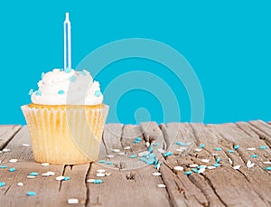 Single cupcake with blue candle and sprinkles