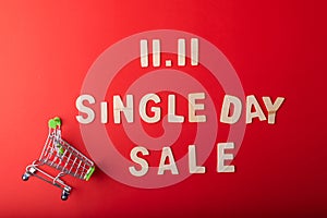 11.11Single day sale. Small cart with 11.11 single`s day sale text was made from wood on red color background. Top view