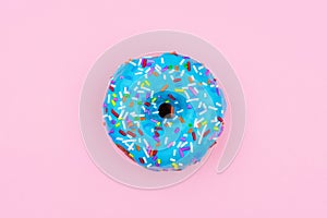 Single donut with pastel blue icing against a pink background