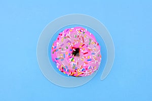 Single donut with pastel pink icing against a blue background