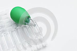 Single dose ampoules of sterile isotonic sea water solution and nasal aspirator on white background, closeup. Space for text