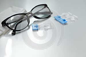 Single dose eye drops, glasses and fabric on table. Space for text