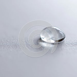 A single drop of water sitting on top of a white surface