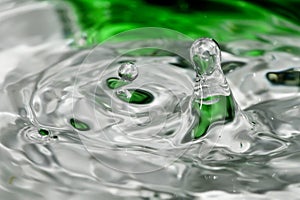 A Single droplet of water falling with green reflection