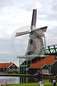 Single dutch windmill with a traditional wooden house in a Netherland`s landscape.