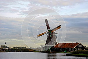 Single Dutch Windmill and wooden house  in a traditional Netherland`s landscape.