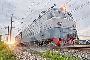 Single electric locomotive on the railway in the evening at sunset.