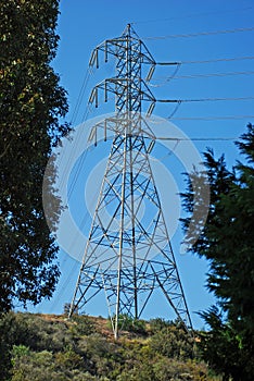 Single electricity transmission tower on a hill.