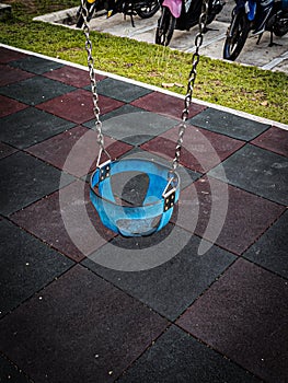 A single, empty blue swing in a playground.