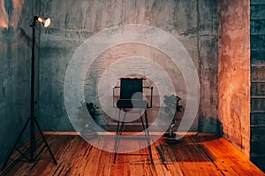 Single empty chair under a spotlight in a room on a stage, director chair, dark and moody toning