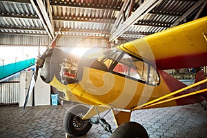 Single-engine propeller airplane standing in hangar with opened motor cabinet