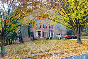 Single-family brick country house with yellow trees in the frontyard. Autumn landscape