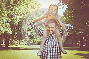 Single father with his daughter in meadow. Little girl sitting o