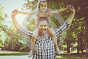 Single father with his daughter in meadow. Little girl sitting o