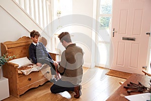 Single Father At Home Getting Son Wearing Uniform Ready For First Day Of School