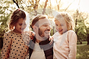 Single father with two little daughters in park.