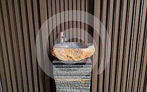 Single faucet and washing basin outside at park with wooden wall background