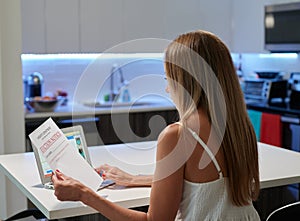 Single female sitting in the kitchen and reading eviction note from sheriff`s department