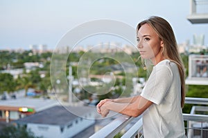 Single female standing outside on residential balcony sunset isolation