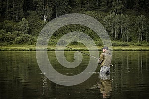 Single fisherman on a calm river is autumn fishing