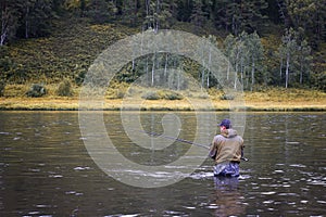 Single fisherman on a calm river is autumn fishing