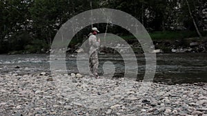 Single fisherman on a stormy river is fishing on a sunny summer day